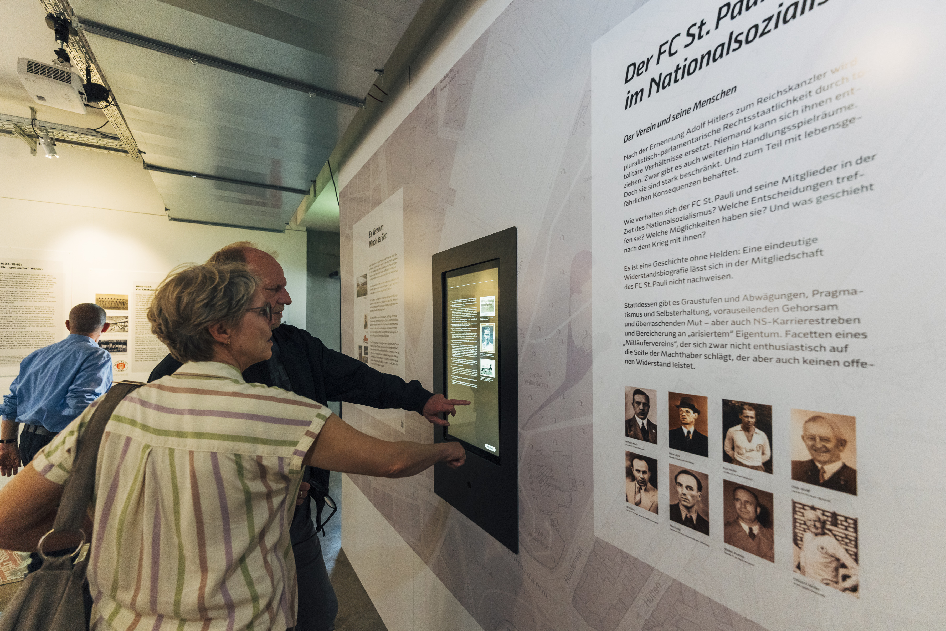 An einem Touchscreen können die Besucher*innen weitere Lebensläufe von Mitgliedern des FC St. Pauli aus den Ausstellungen „Fußball in Trümmern“ und „Lebenswege“ des FC St. Pauli-Museums erkunden.